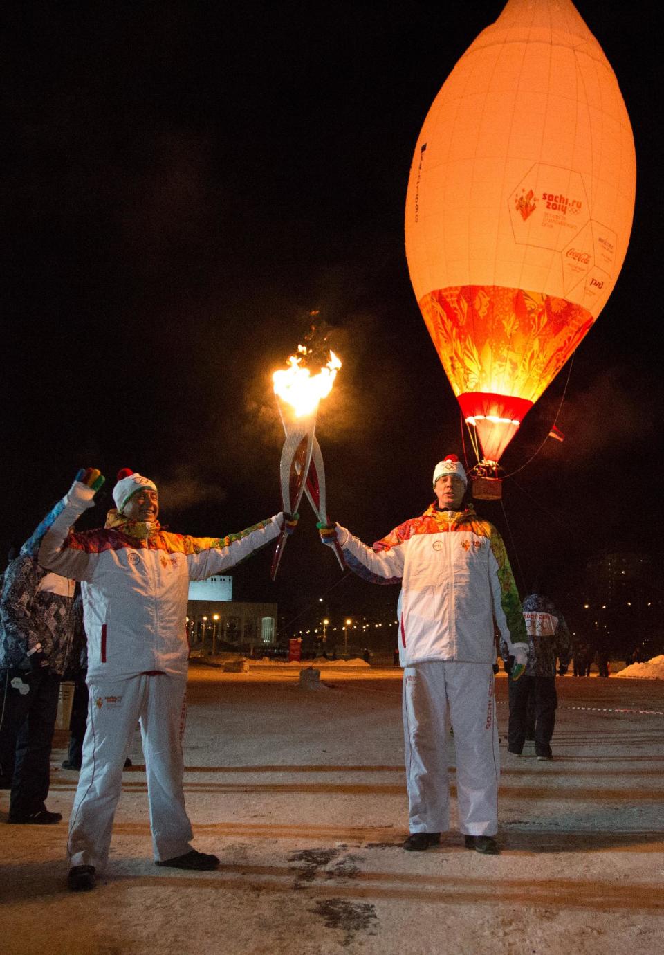 In this photo taken on Jan. 4, 2014. and provided by Olympictorch2014.com, Olympic torch bearers Alexander Tuchkin, left, and Vasiliy Makarov hold Olympic torches during the torch relay in Perm, Russia. The relay for the Sochi Winter Games, which began on Oct. 7 2013 in Moscow, will pass through many cities that showcase the historical, cultural and ethnic richness of Russia. (AP Photo/Olympictorch2014.com)