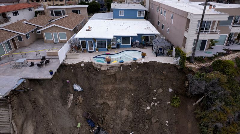 FILE PHOTO: A backyard pool hangs on cliffside after torrential rains hits California beachtown