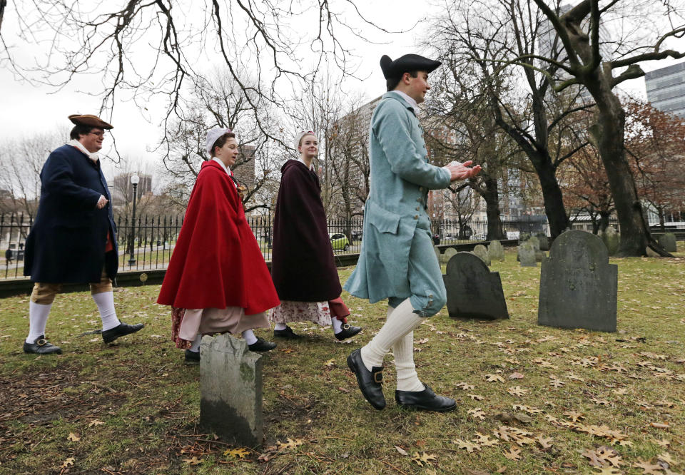 Actor-interpreters from the Boston Tea Party Ships and Museum, from left, Tim Lawton, Jillian Couillard, Sierra Grabowska and Stephen Chueka walk after placing commemorative markers, Tuesday, Nov. 27, 2018, at Central Burying Ground on Boston Common at the graves of participants in the Dec. 16, 1773 protest known as the Boston Tea Party. This year is the 245th anniversary of the protest during which colonists protesting taxation without representation threw British tea into Boston Harbor, considered a pivotal event that led to the American Revolution. (AP Photo/Elise Amendola)