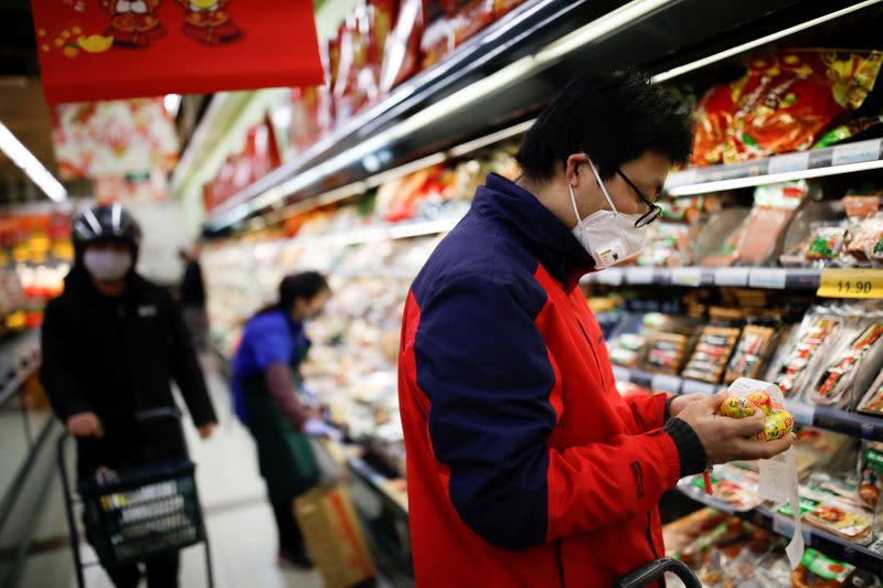 People wearing face masks look for products at a supermarket, as the country is hit by an outbreak of the new coronavirus, in Beijing