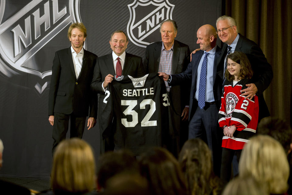 NHL commissioner Gary Bettman, center left, holds a jersey after the NHL Board of Governors announced Seattle as the league's 32nd franchise, Tuesday, Dec. 4, 2018, in Sea Island Ga.. Joining Bettman, from left to right, is Jerry Bruckheimer, David Bonderman, David Wright, Tod Leiweke and Washington Wild youth hockey player Jaina Goscinski. (AP Photo/Stephen B. Morton)