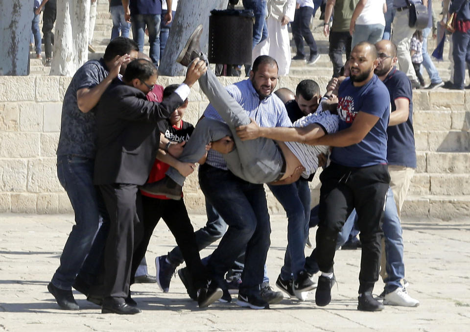 Palestinians carry injured person during clashes with Israeli police at al-Aqsa mosque compound in Jerusalem, Sunday, Aug 11, 2019. Clashes have erupted between Muslim worshippers and Israeli police at a major Jerusalem holy site during prayers marking the Islamic holiday of Eid al-Adha. (AP Photo/Mahmoud Illean)