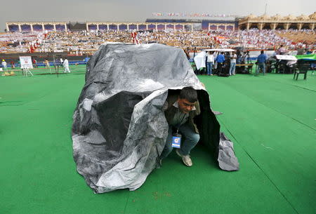An attendee comes out from a plastic sheet which was used to take shelter from rains at the venue of World Culture Festival on the banks of a river in New Delhi, India, March 11, 2016. REUTERS/Adnan Abidi