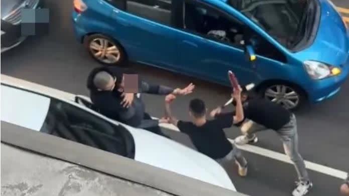 3名黑衣男子，只因行車糾紛，下車後竟持棒球棍及廟會榔頭，就在路邊毆打另一部車的駕駛。（圖/翻攝畫面)