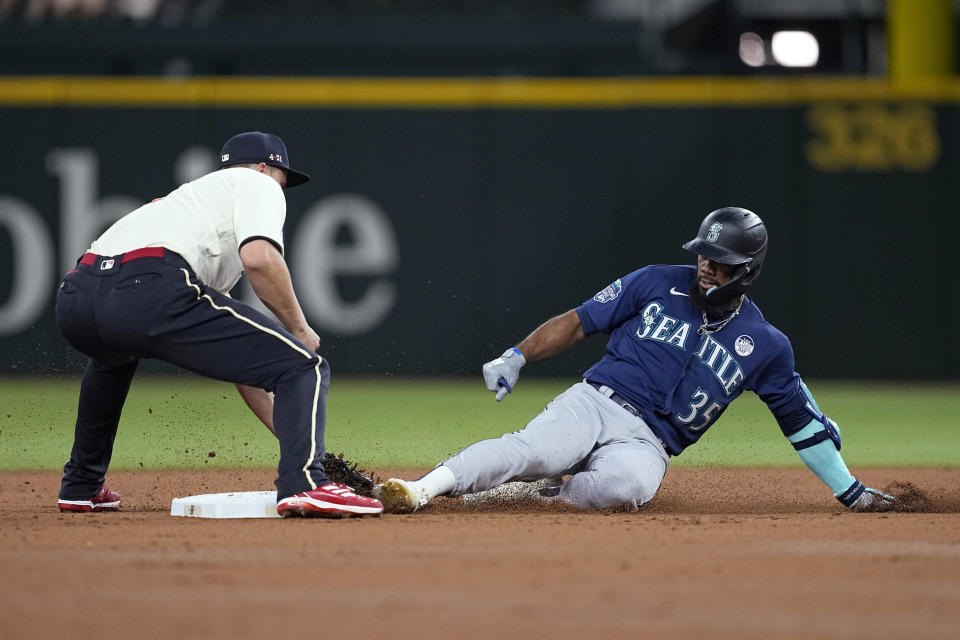 Texas Rangers shortstop Corey Seager, left, reaches down to tag out Seattle Mariners' Teoscar Hernandez (35), who was trying to stretch a single into a double during the third inning of a baseball game Friday, June 2, 2023, in Arlington, Texas. (AP Photo/Tony Gutierrez)