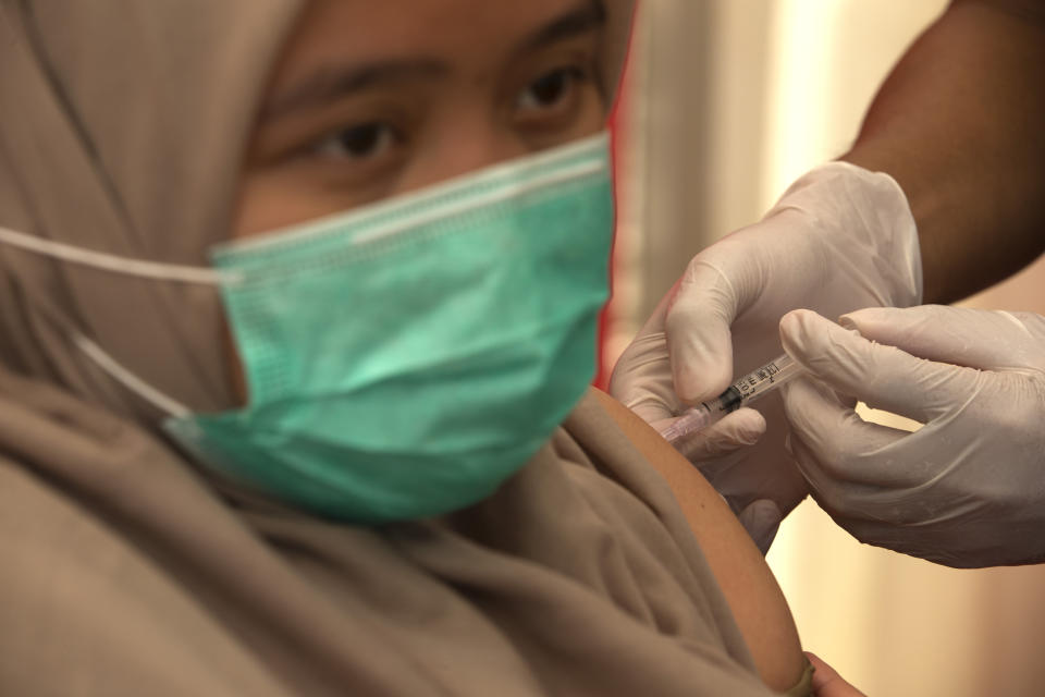 A health worker receives a shot of COVID-19 vaccine at a hospital in Bali, Indonesia on Thursday, Jan. 14, 2021. Indonesia started vaccinating health workers and public servants against COVID-19 on Thursday, a day after President Joko Widodo received the first shot of China's Sinovac Biotech vaccine. The Health Ministry is planning to vaccinate more than 1.3 millions health workers and 17.4 millions public officers in the first stage in the world's fourth most populated country. (AP Photo/Firdia Lisnawati)