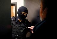 Lawyer Svetlana Davydova shows her identification to a law enforcement officer standing outside an apartment of Russian opposition leader Alexei Navalny in Moscow