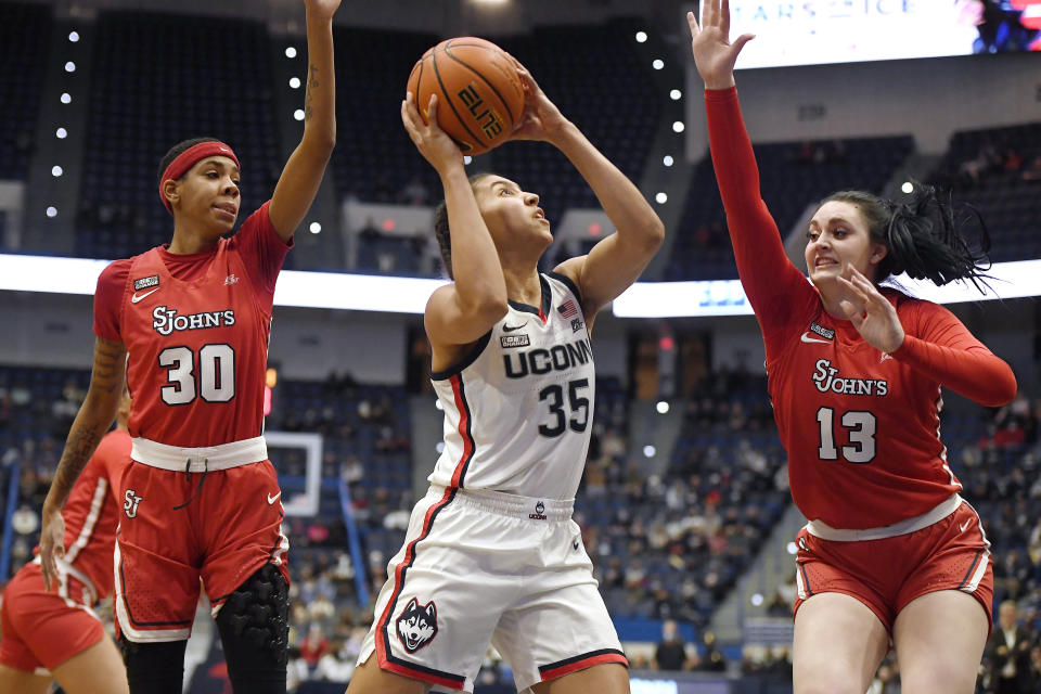 Connecticut's Azzi Fudd (35) looks to shoot as St. John's Kadaja Bailey (30) and Danielle Cosgrove (13) defend in the first half of an NCAA college basketball game, Friday, Feb. 25, 2022, in Hartford, Conn. (AP Photo/Jessica Hill)