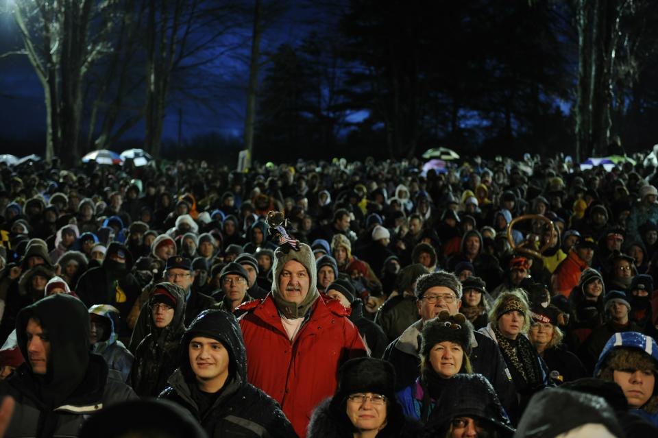 PUNXSUTAWNEY, PA - FEBRUARY 2: A crowd gathers to watch Punxsutawney Phil come out of his burrow during the 125th annual Groundhog Day festivities on February 2, 2011 in Punxsutawney, Pennsylvania. Phil came out and did not see his shadow predicting an early spring. Groundhog Day is a popular tradition in the United States and Canada. A smaller than usual crowd this year of less than 15,000 people spent a night of revelry awaiting the sunrise and the groundhog's exit from his winter den. If Punxsutawney Phil sees his shadow he regards it as an omen of six more weeks of bad weather and returns to his den. Early spring arrives if he does not see his shadow causing Phil to remain above ground. (Photo by Jeff Swensen/Getty Images)