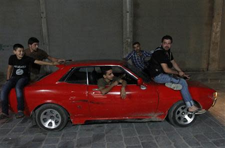 A boy sits with Free Syrian Army fighters on a car in front of their headquarter in the old city of Aleppo September 9, 2013. REUTERS/Hamid Khatib