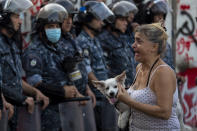 An anti-government protester cries as she holds her dog during ongoing protests in Beirut, Lebanon, Thursday, July 2, 2020. Major retailers in Lebanon announced Thursday they will temporarily close in the face of an increasingly volatile currency market and their inability to set prices while the local currency tumbles before the dollar. (AP Photo/Hassan Ammar)