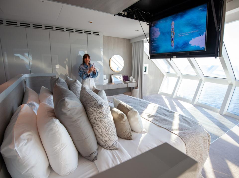 a bed facing panoramic windows and a TV coming down from the wall in the Iconic suite on the Celebrity Apex cruise ship