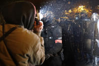 FILE - In this Nov.21, 2020 file photo a demonstrator takes a picture of policemen during a protest against bill on police images, in Paris. As videos helped reveal many cases of police brutality, French civil rights activists voiced fears that a new security law would threaten efforts by people from minorities and poor neighborhoods to document incidents involving law enforcement officers. French President Emmanuel Macron's government is pushing a new security bill that would notably make it illegal to publish images of officers with intent to cause them harm. (AP Photo/Christophe Ena, File)