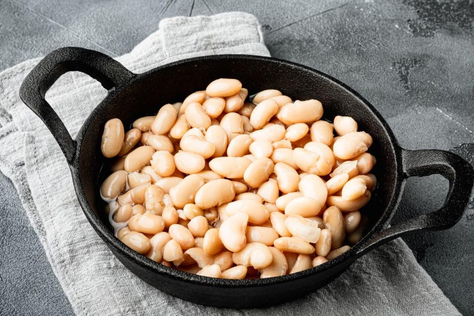 white canned beans set, in cast iron frying pan, on gray stone background