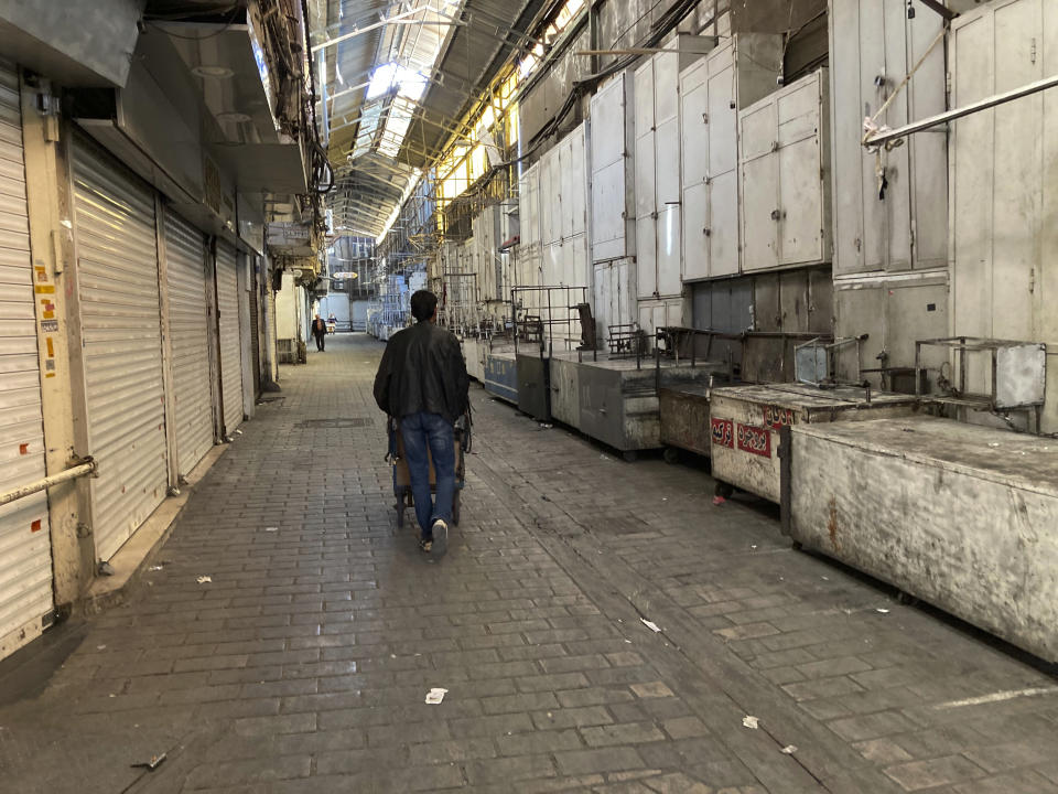 A man pushes his cart past closed shops of Tehran's Grand Bazaar, Iran, Tuesday, Nov. 15, 2022. Many shops at Grand Bazaar in Iran's capital city were closed Tuesday amid strike calls following the September death of a woman who was arrested by the country's morality police. (AP Photo/Vahid Salemi)