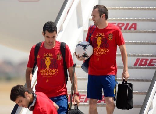 Los jugadores de la selección española de fútbol Cesc Fábregas (izq), Sergio Busquets (c) y Andrés Iniesta descienden de un avión en el aeropuerto de Madrid-Barajas el 2 de julio, un día después de haberse proclamado campeones de Europa. (AFP/Archivo | Dani Pozo)