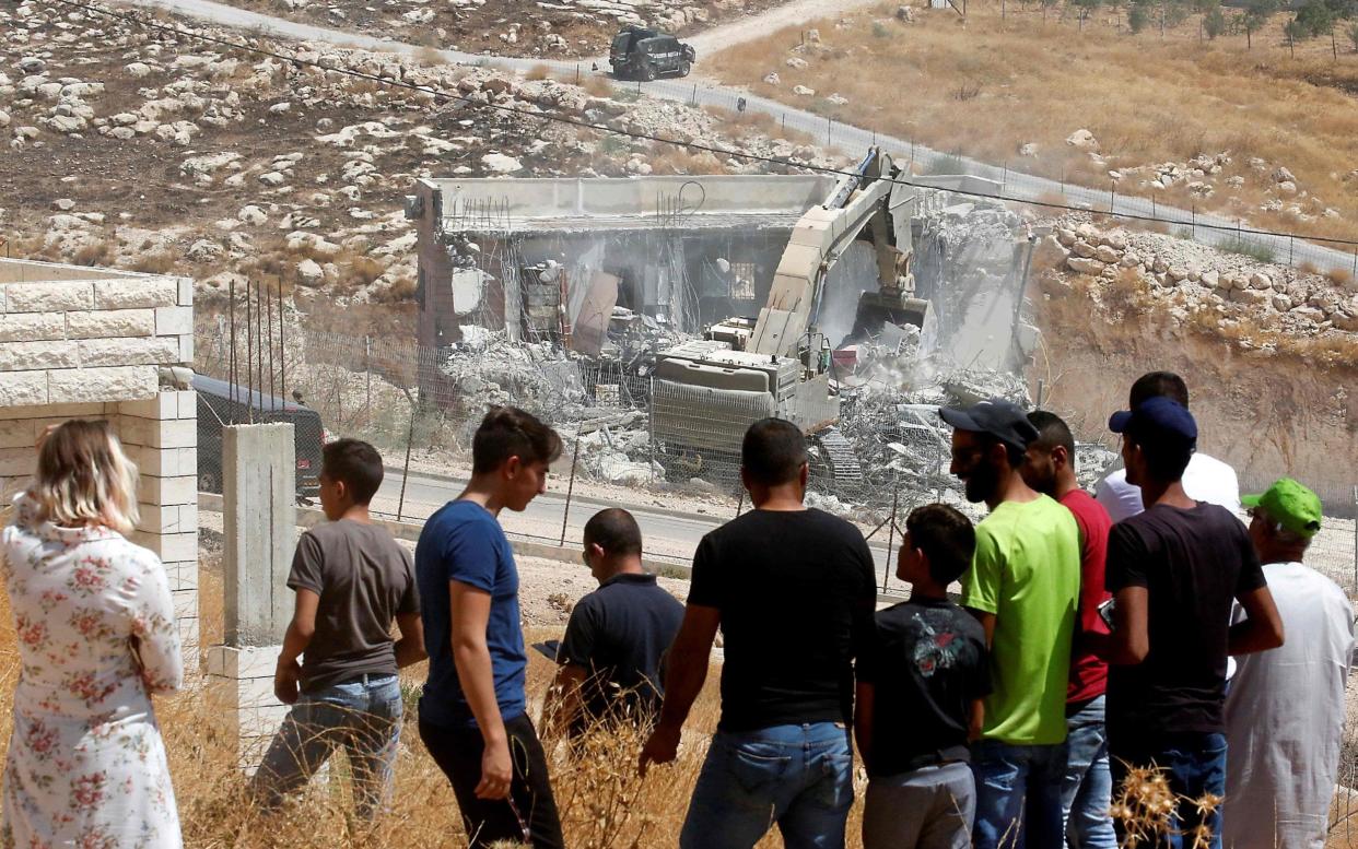 Palestinians watch as Israeli security forces tear down a Palestinian building - AFP