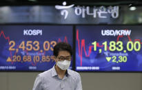 A currency trader walks near screens showing the Korea Composite Stock Price Index (KOSPI), left, and the foreign exchange rate between U.S. dollar and South Korean won at the foreign exchange dealing room in Seoul, South Korea, Thursday, Aug. 13, 2020. Asian shares were mostly higher on Thursday, cheered by the rally on Wall Street that's likely a boon for export-driven regional economies, even as investors worry about the coronavirus pandemic. (AP Photo/Lee Jin-man)