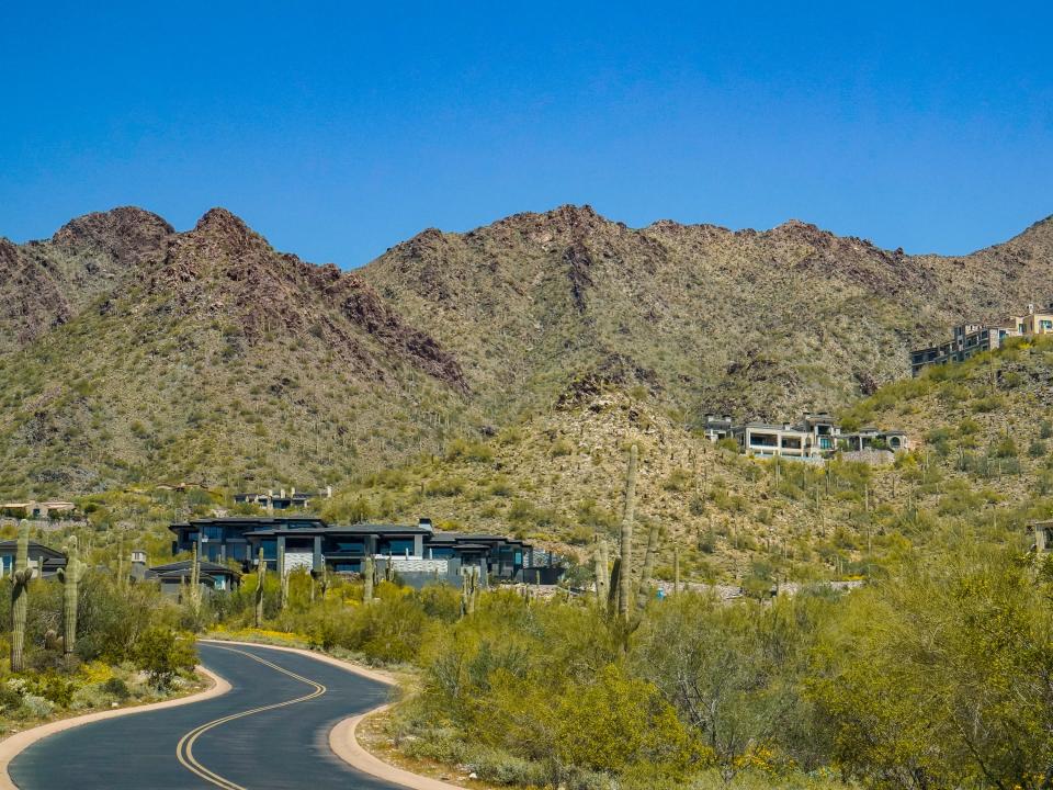 Mansions off of a winding road on a mountain dotted with bushes and cacti in DC Ranch in Scottsdale