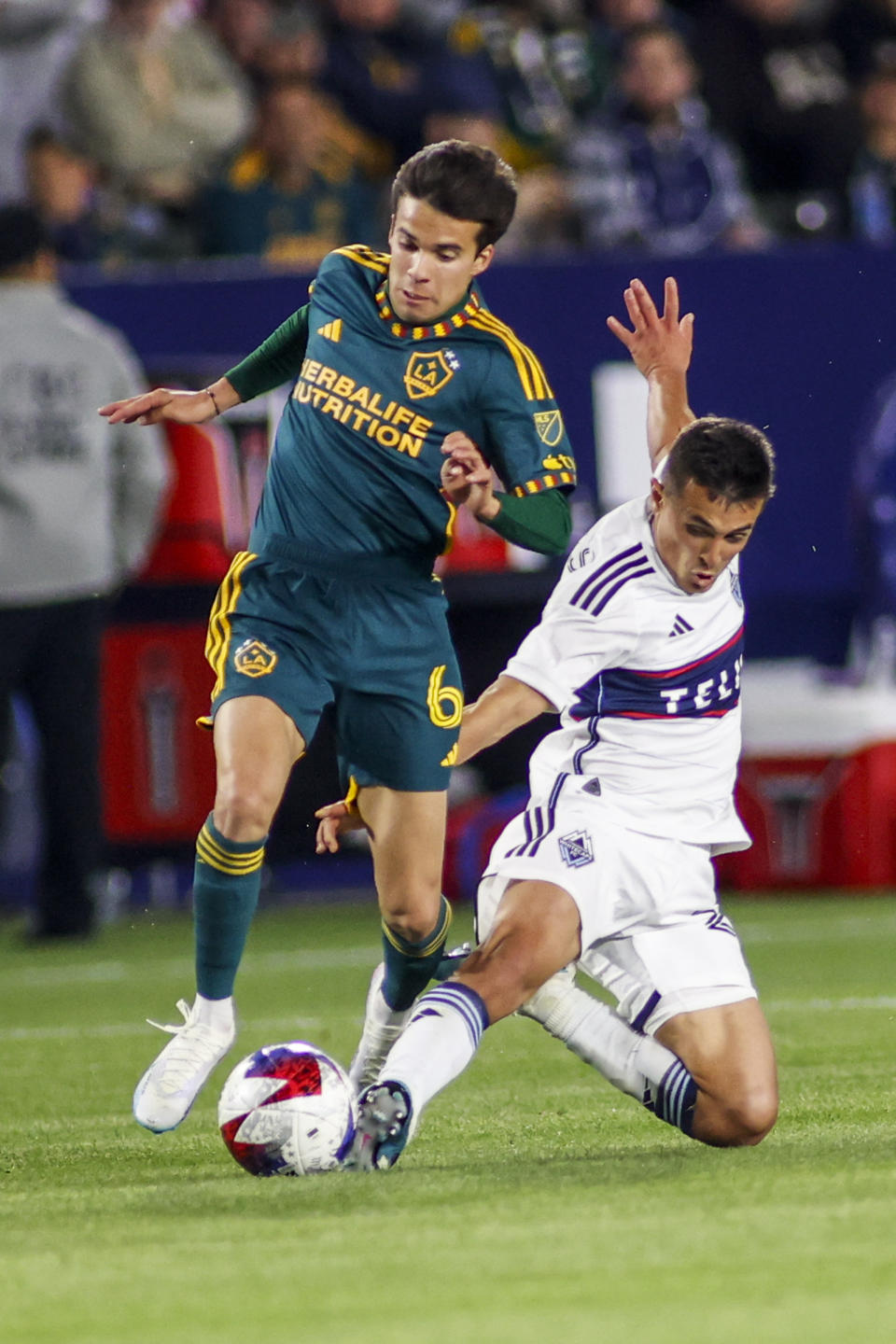 LA Galaxy midfielder Riqui Puig, left, and Vancouver Whitecaps midfielder Andrés Cubas vie for the ball during the second half of an MLS soccer match in Carson, Calif., Saturday, March 18, 2023. (AP Photo/Ringo H.W. Chiu)