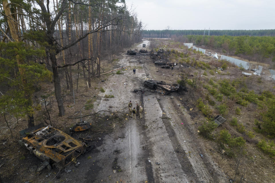 FILE - Ukrainian soldiers stand amid destroyed Russian armor vehicles in the outskirts of Kyiv, Ukraine March 31, 2022. Russian forces shelled Kyiv suburbs, two days after the Kremlin announced it would significantly scale back operations near both the capital and the northern city of Chernihiv to increase trust between the two sides. (AP Photo/Rodrigo Abd, File)