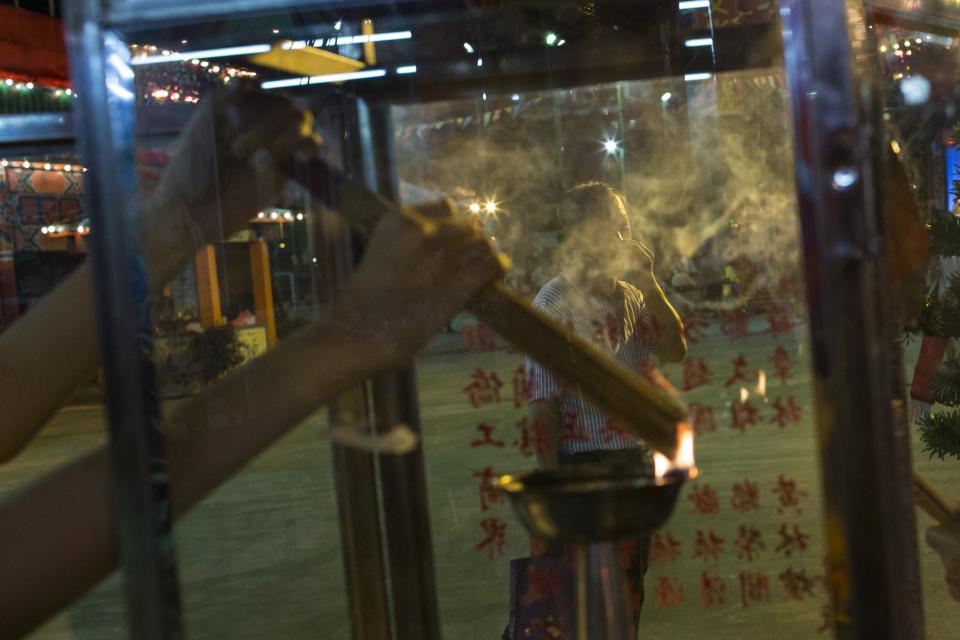 A woman burns incense sticks during the Chinese Hungry Ghost Festival in Hong Kong August 8, 2014. The Ghost Festival, also known as Yu Lan, is a traditional Chinese festival on the 15th night of the seventh month of the Chinese calendar. In Chinese tradition, the month is regarded as the Ghost Month, in which ghosts and spirits, including those of deceased ancestors, come out from the lower realm to visit the living. Worshippers prepare ritualistic food offerings and burn joss paper - a paper form of material items - for the ghost. Other paper items in the form of clothes, gold and other fine goods are also burnt for the visiting spirits of the ancestors to show respect.REUTERS/Tyrone Siu (CHINA - Tags: RELIGION SOCIETY)