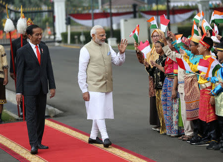 Indian Prime Minister Narendra Modi waves at Indonesian school children waving Indonesian and Indian national flags as Indonesian President Joko Widodo looks on during the welcoming ceremony at Merdeka Palace in Jakarta, Indonesia May 30, 2018. REUTERS/Dita Alangkara/Pool