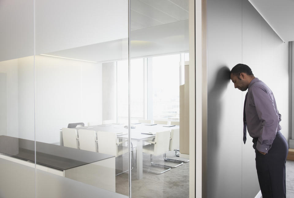 Man with head against wall in conference room