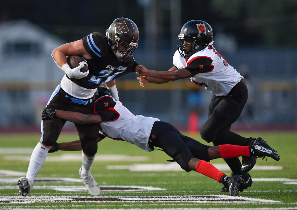 ER/Gananda's Caleb Carpenter, left, tries to break free from Vertus' Willie Daniels, right, and Josiah Granville during a regular season game at East Rochester High School, Saturday, Sept. 3, 2022.