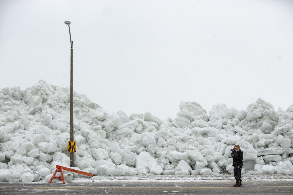 A man photographs a massive build up of ice that was pushed onto the shore of Mather Park in Fort Erie, Ont., Monday, February 25, 2019. A windstorm Sunday broke an ice boom in Lake Erie and allowed the ice, which was floating on the water at the mouth of the Niagara River, to shove over the retaining wall and onto the shore and the roadway above. (Tara Walton/The Canadian Press via AP)