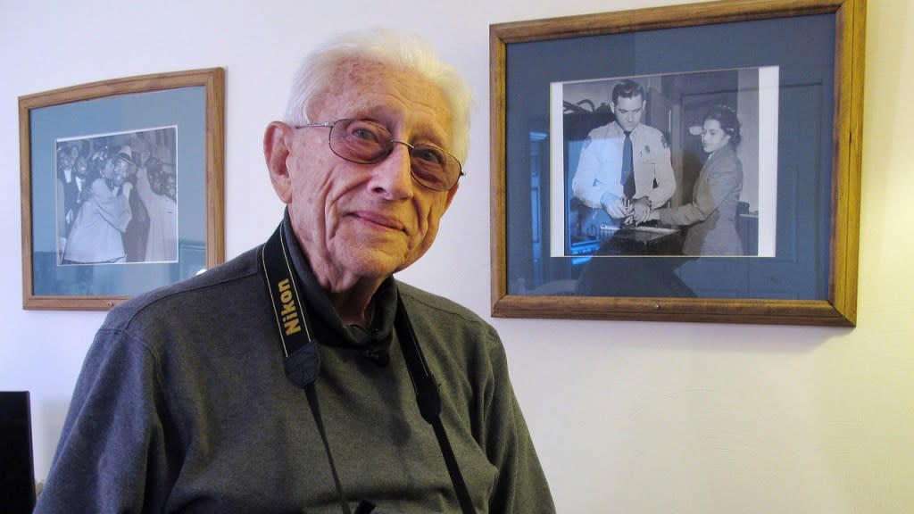 Former Associated Press photographer Gene Herrick, who died Friday at age 97, poses between two of his most famous pictures at his home in Rocky Mount, Virginia in Feb. 2018. (Photo: Allen G. Breed/AP, file)