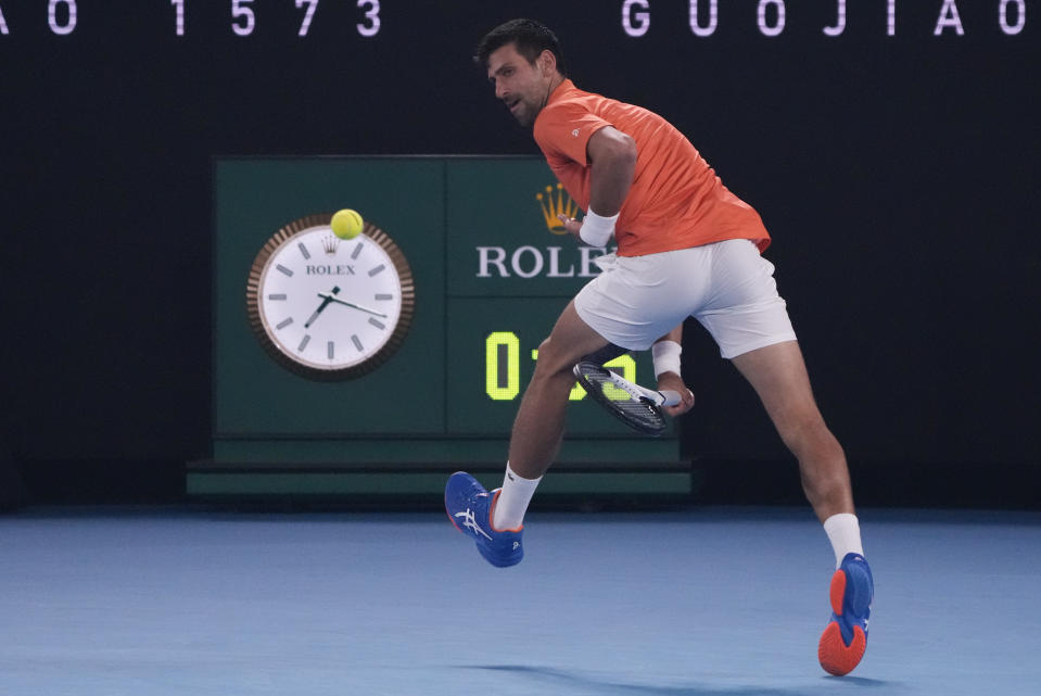 En foto del viernes 13 de enero del 2023, el serbio Novak Djokovic realiza una jugada entre las piernas durante un duelo de exhibición en el Rod Laver Arena ante el australiano Nick Kyrgios. (AP Foto/Mark Baker)