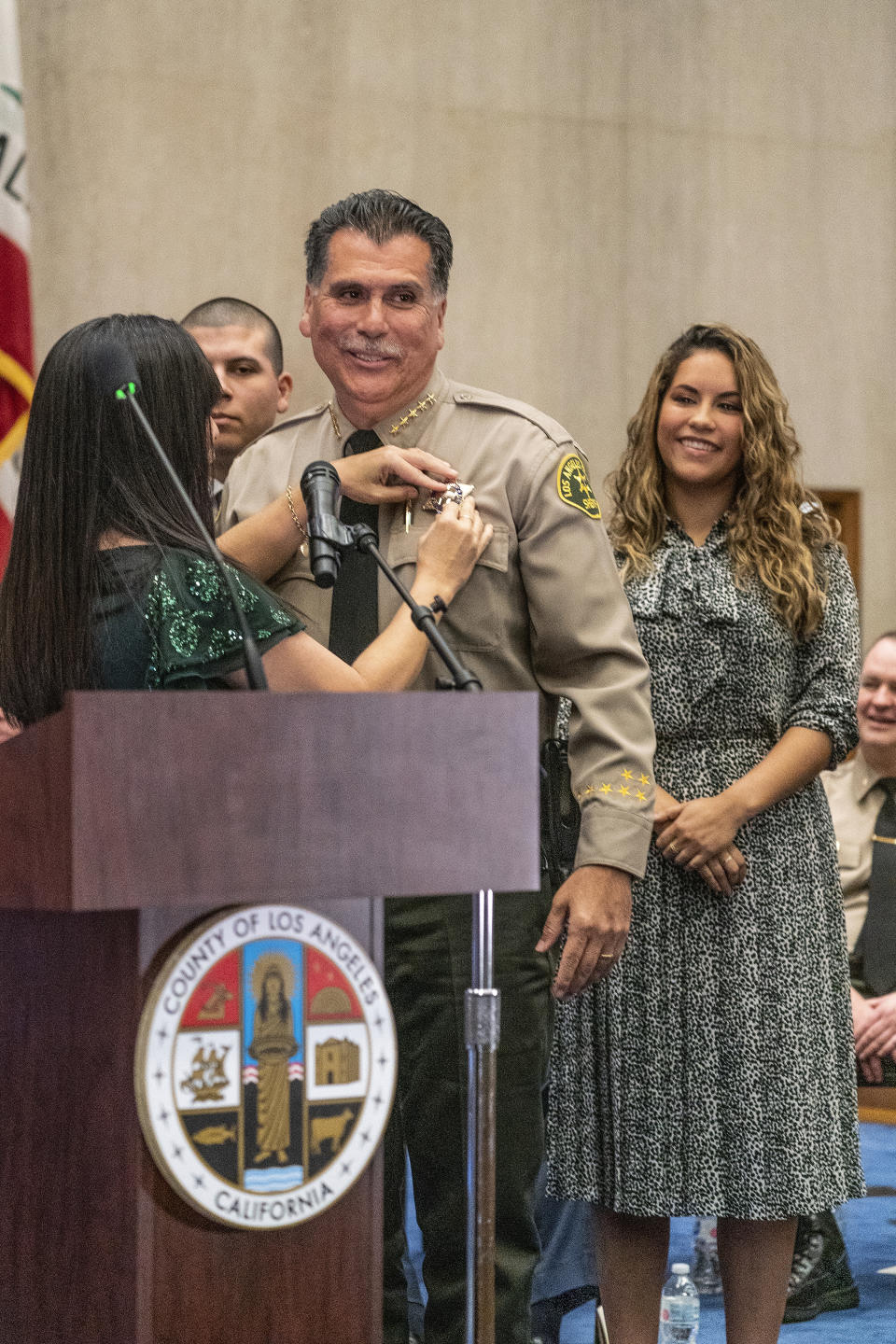 New Los Angeles County Sheriff Robert Luna gets his new sheriff's badge pinned by his wife, left, in Los Angeles, Saturday, Dec. 3, 2022. At right is his daughter Cesie Alvarez. (AP Photo/Damian Dovarganes)