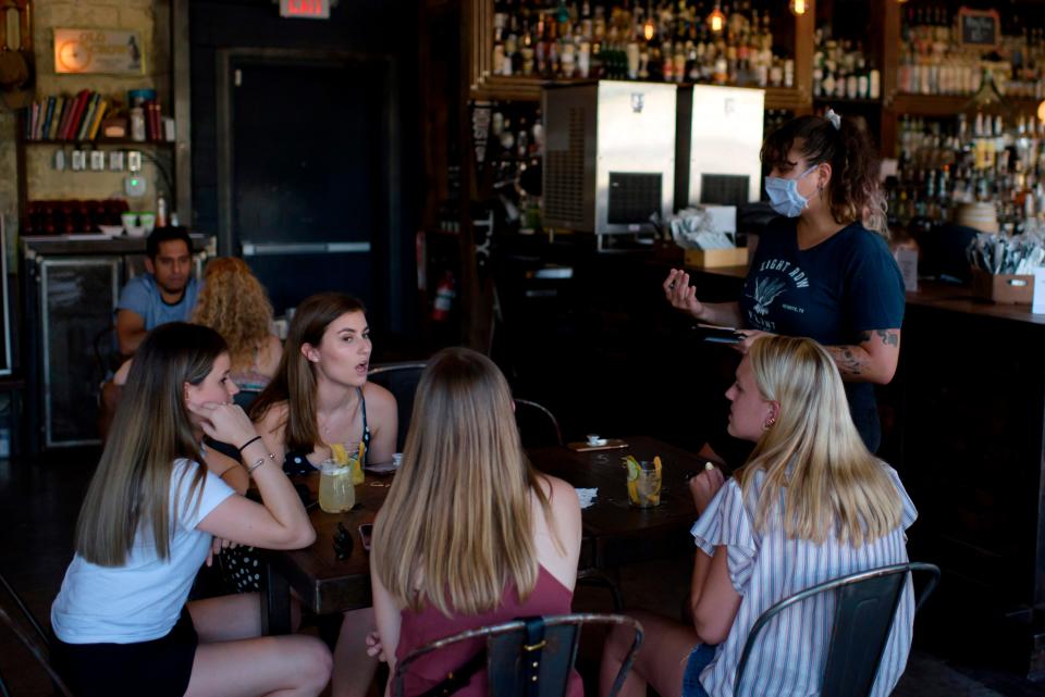 A server wearing a face mask takes orders from a table of customers at Eight Row Flint in Houston on May 22 amid the coronavirus pandemic.