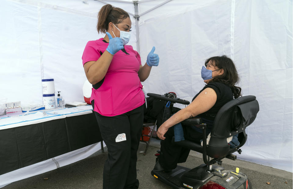 Veronica Lopez, who has Spina bifida, and who is a resident of the 90255 ZIP code, is vaccinated by medical assistant Keyaira Excoe at the St. John's Well Child and Family Center's COVID-19 vaccination site at the East Los Angeles Civic Center in Los Angeles, Thursday, March 4, 2021. California will begin setting aside 40% of all vaccine doses for the state's most vulnerable neighborhoods in an effort to inoculate people most at risk from the coronavirus more quickly. (AP Photo/Damian Dovarganes)