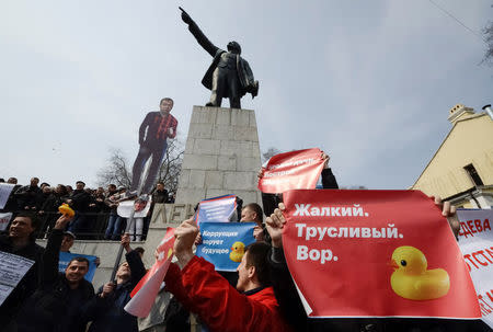 Opposition supporters hold posters and a cutout figure depicting Prime Minister Dmitry Medvedev during a rally in front of a monument of Soviet state founder Vladimir Lenin in Vladivostok. The poster on the right reads: Pathetic. Cowardly. Thief. REUTERS/Yuri Maltsev