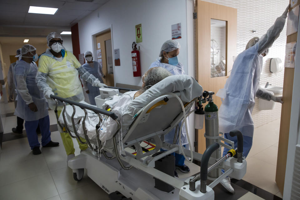 Health workers move a COVID-19 patient to a ward of Dr. Ernesto Che Guevara hospital in Marica, Brazil, Wednesday, January 26, 2022. (AP Photo/Bruna Prado)