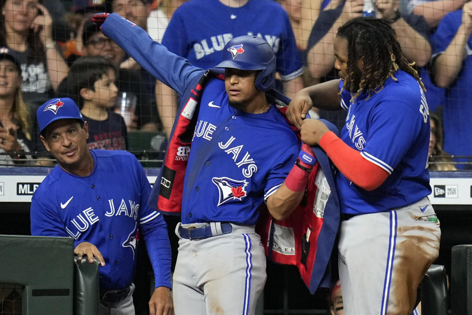 Toronto Blue Jays' Vladimir Guerrero Jr., right, helps Santiago Espinal put on a home run jacket after Espinal hit a solo homer during the fifth inning of the team's baseball game against the Houston Astros, Friday, April 22, 2022, in Houston. (AP Photo/Eric Christian Smith)