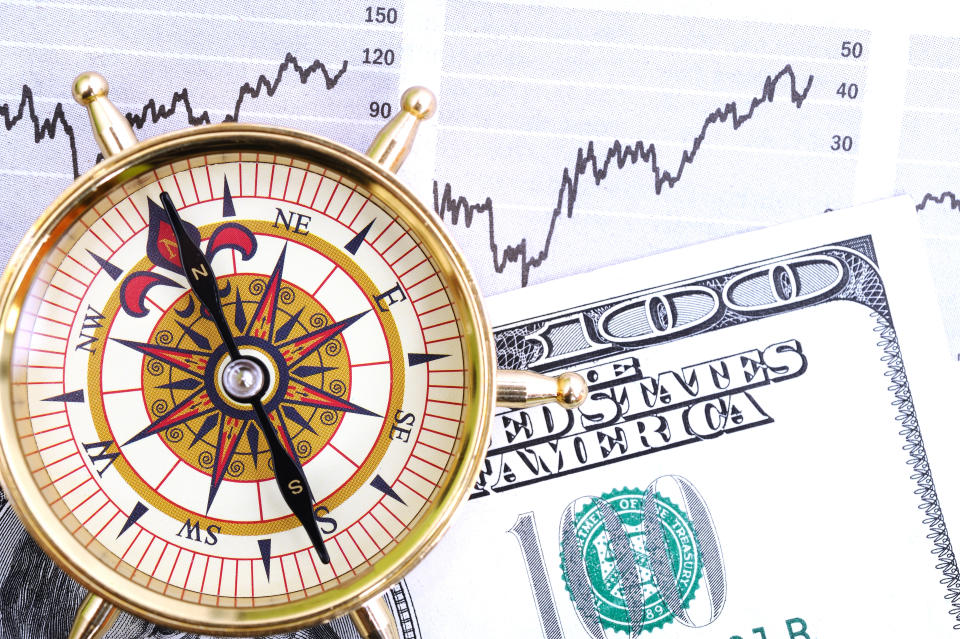 Compass and US dollars on financial page.