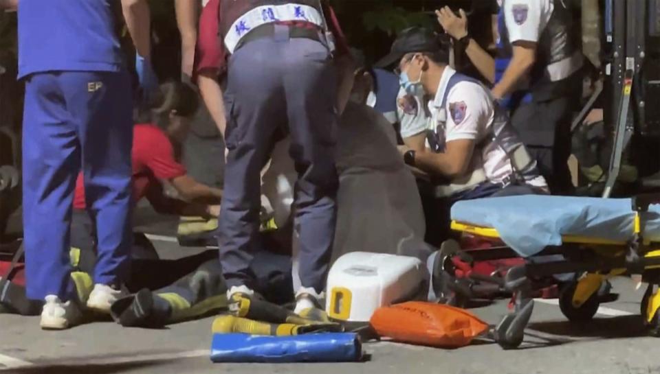 In this image made from video footage run by EBC, medical workers treat an injured firefighter near a factory of golf ball manufacturer Launch Technologies Co. in the southern county of Pingtung in Taiwan on Friday, Sept. 22, 2023. The golf ball factory fire has left multiple people killed, and the victims include several firefighters, according to Taiwanese media reports. (EBC via AP)