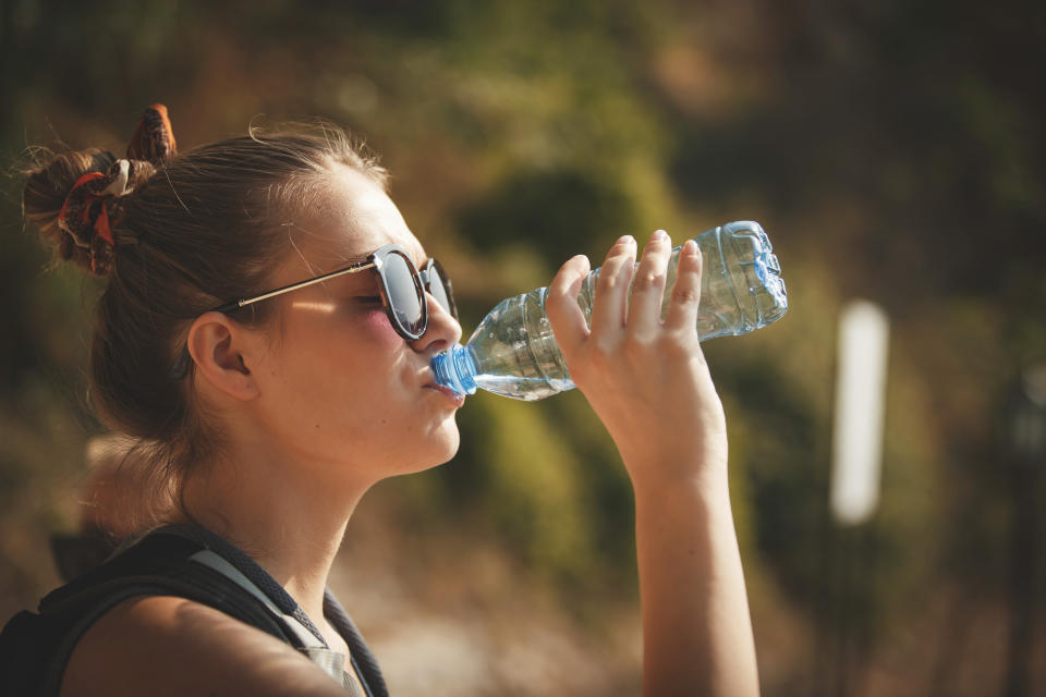 Femme buvant de l'eau d'une bouteille en plastique.