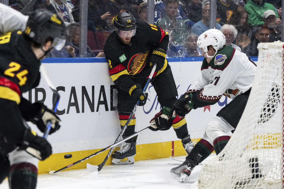 Vancouver Canucks' Sam Lafferty (18) and Arizona Coyotes' Josh Doan (91) vie for the puck during the third period of an NHL hockey game Wednesday, April 10, 2024, in Vancouver, British Columbia. (Ethan Cairns/The Canadian Press via AP)