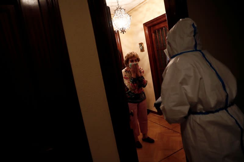 Purificacion Gutierrez Nogal blows kisses to Comunidad de Madrid home care nurse Maria Jesus Santamaria in full protective gear as she arrives to treat Purificacion's sister Concepcion, who is sick with coronavirus, in Madrid