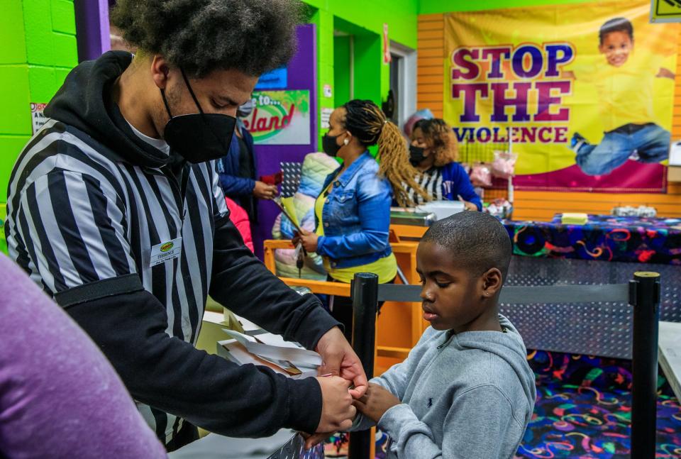 Terrence Hackett II (left), a junior at Ben Davis High School, places a wrist band on a young skater Wednesday, Feb. 16, 2022, during a school skate at Skateland on Indianapolis' west side.