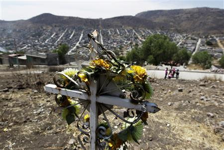 A cross erected in memory of murdered girls stands in a vacant field overlooking Ecatepec on the outskirts of Mexico City April 9, 2013. REUTERS/Henry Romero