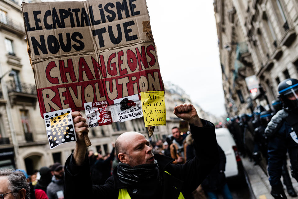 A demonstrator carries a sign reading 'Capitalism is killing us!' at a pension-reform strike in Paris on 9 January
