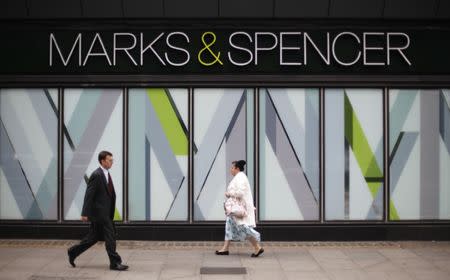 Pedestrians walk past an M&S shop in northwest London July 8, 2014. REUTERS/Suzanne Plunkett/File photo