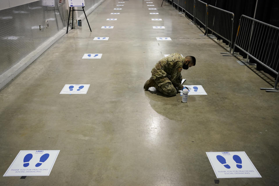 A member of the Nevada National Guard installs social distancing stickers while setting up a new temporary coronavirus testing site Monday, Aug. 3, 2020, in Las Vegas. (AP Photo/John Locher)