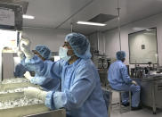 Production personnel perform a visual inspection of filled vaccine vials inside the Incepta plant on the outskirts of Dhaka in Bangladesh Saturday Feb. 13, 2021. In an industrial neighborhood on the outskirts of Bangladesh's largest city lies a factory with gleaming new equipment imported from Germany, its immaculate hallways lined with hermetically sealed rooms. Yet the factory is operating at just a quarter of its capacity. It is one of three factories that The Associated Press found on three continents whose owners say they could start producing hundreds of millions of COVID-19 vaccines on short notice if only they had the blueprints and technical know-how. (AP Photo/Al-emrun Garjon)