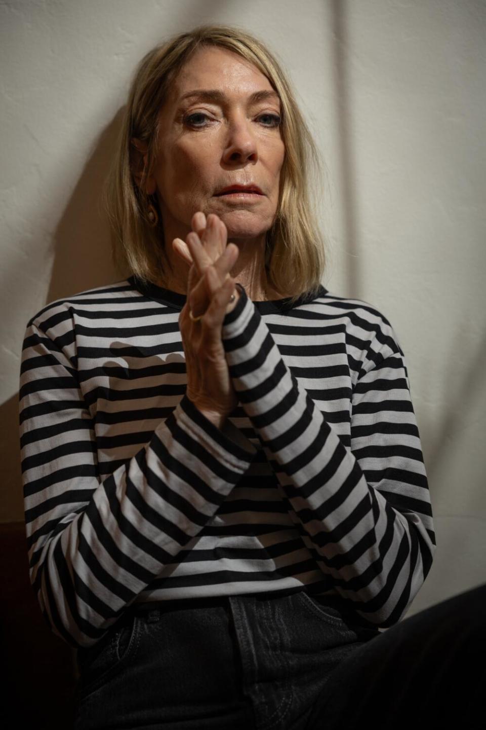A woman in black and white striped shirt looks directly into the camera.